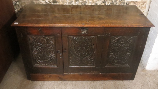 An 18th century large oak blanket chest with hinged plank top, a later tri-panelled carved front.