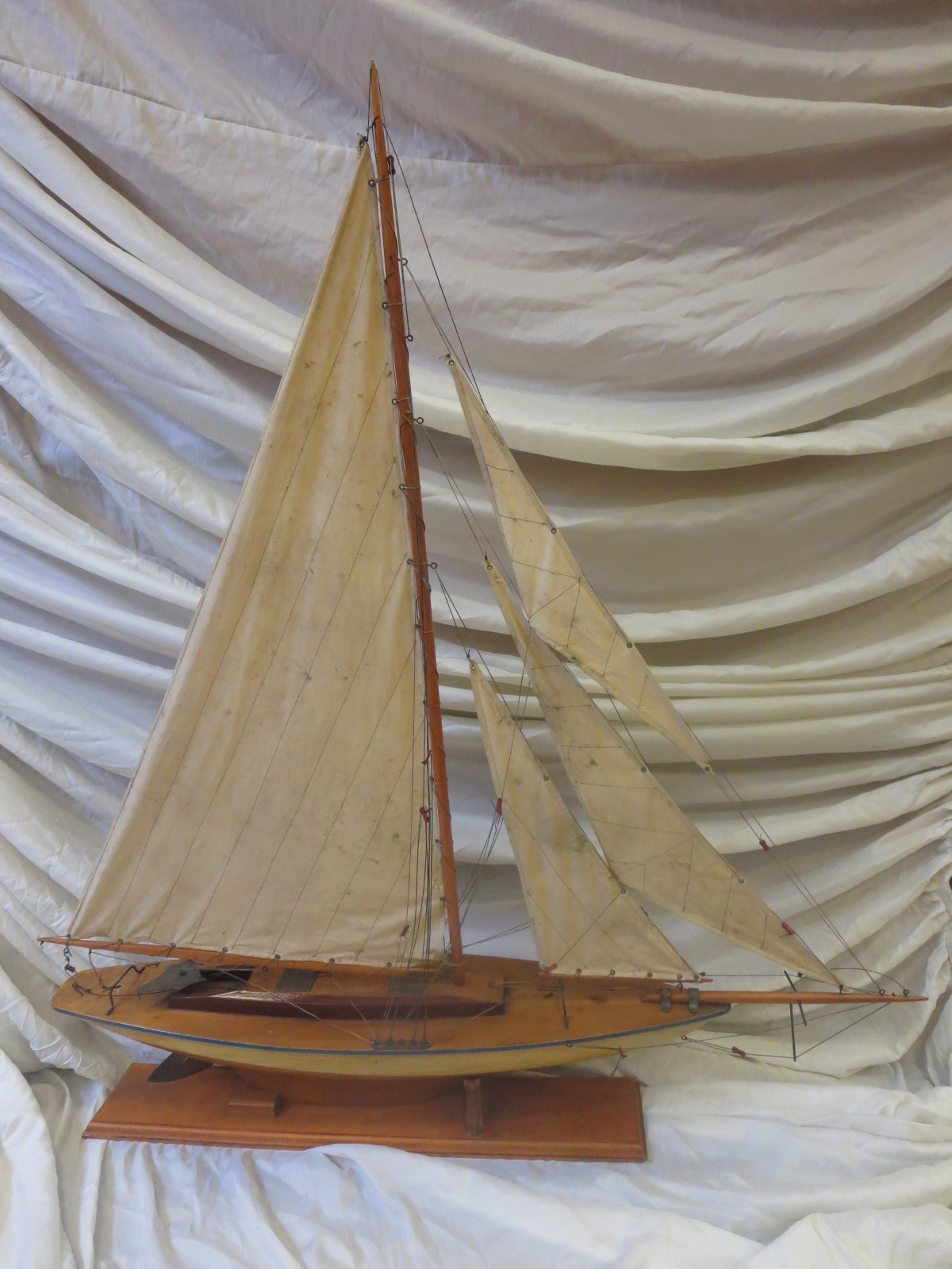 A white and orange painted hand built single masted pond yacht, fully decked, and with brass