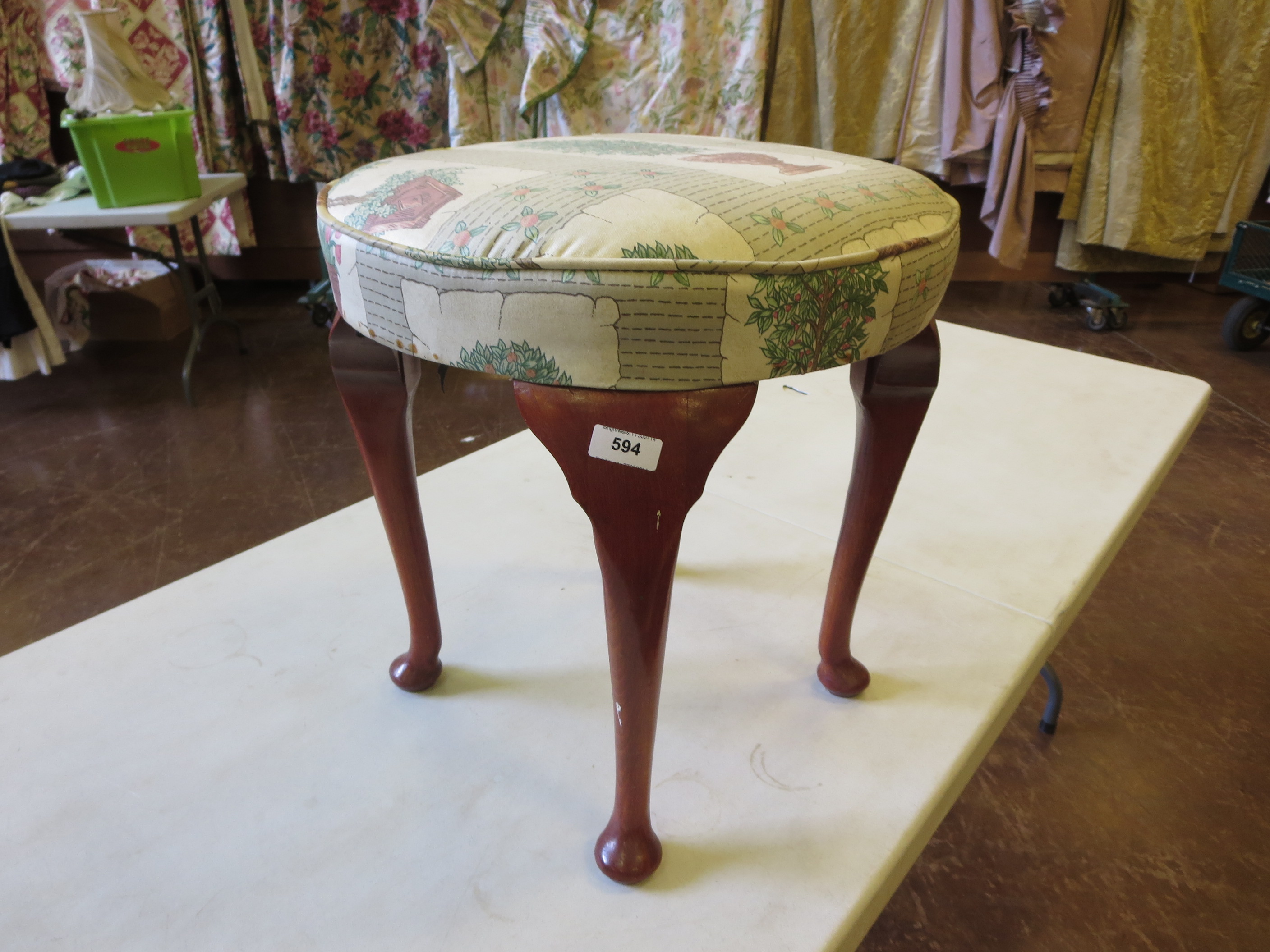 A round stool with cabriole style legs