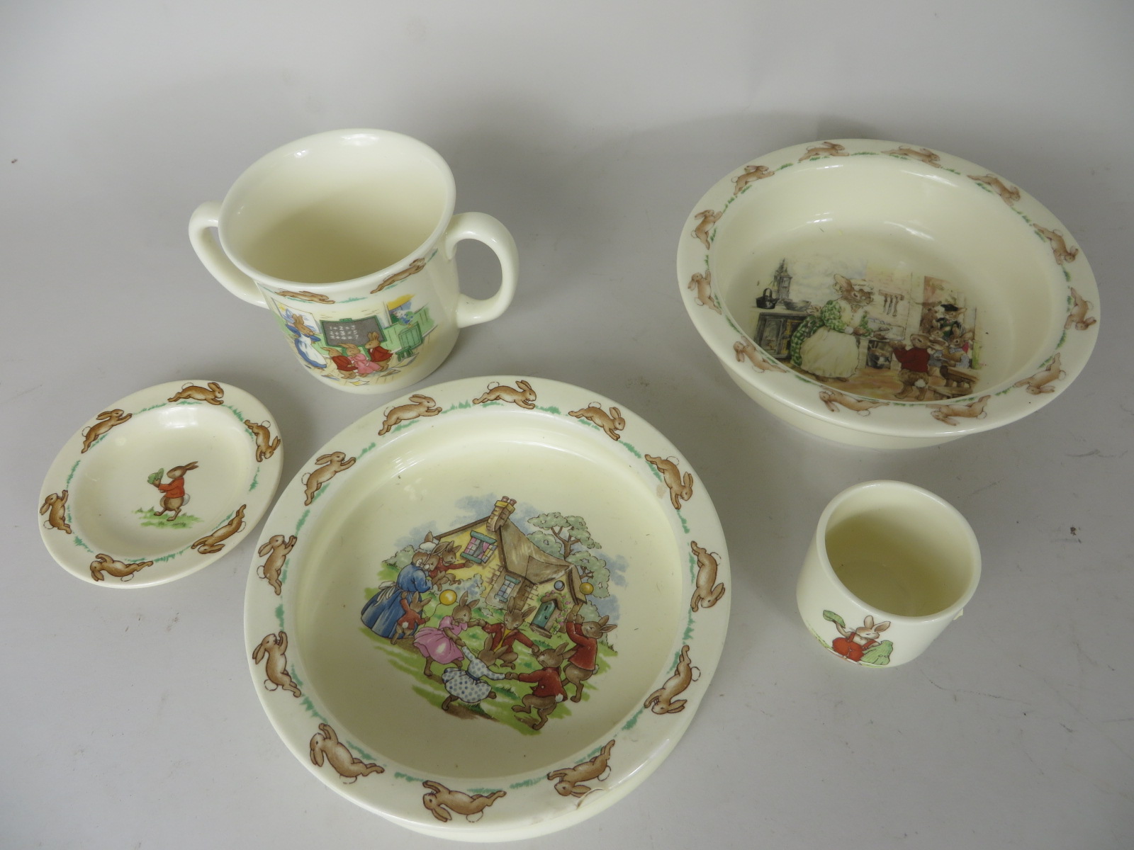 A Royal Doulton Bunnykins two handled mug, egg cup, two dishes and a miniature plate. All with