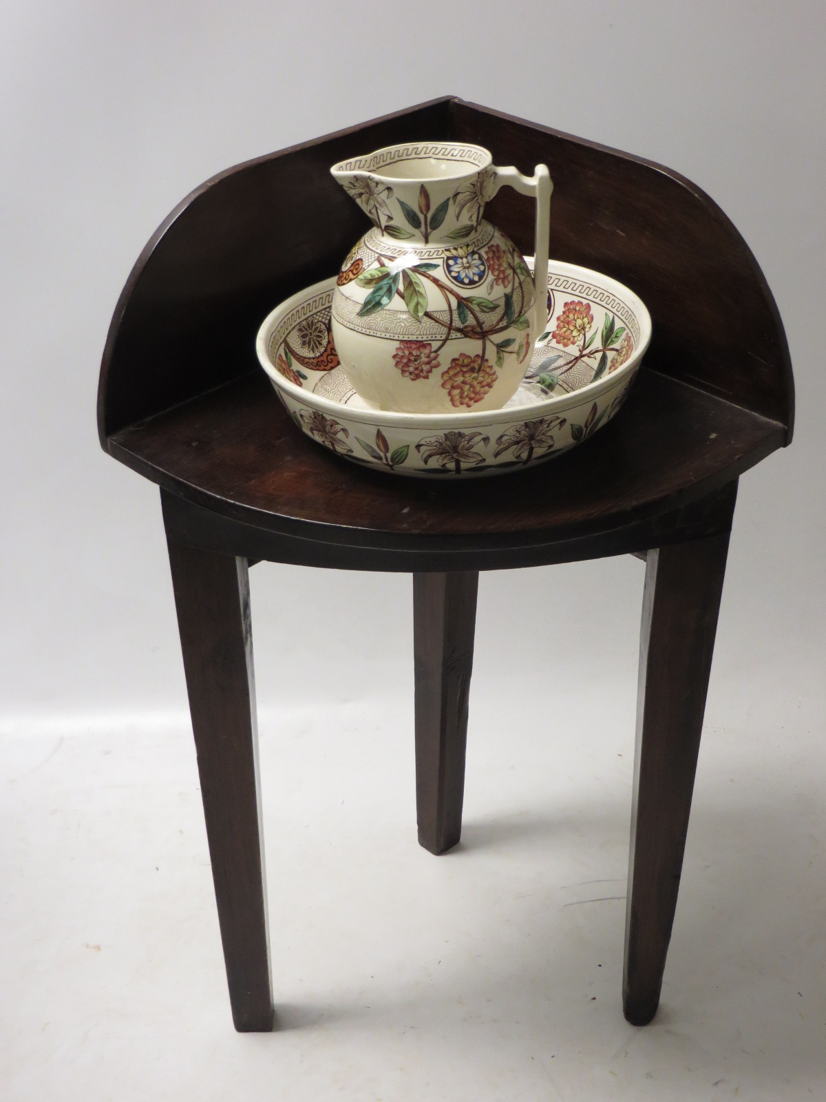 A child’s unusual corner washstand with its small jug and basin. The earthenware polychrome
