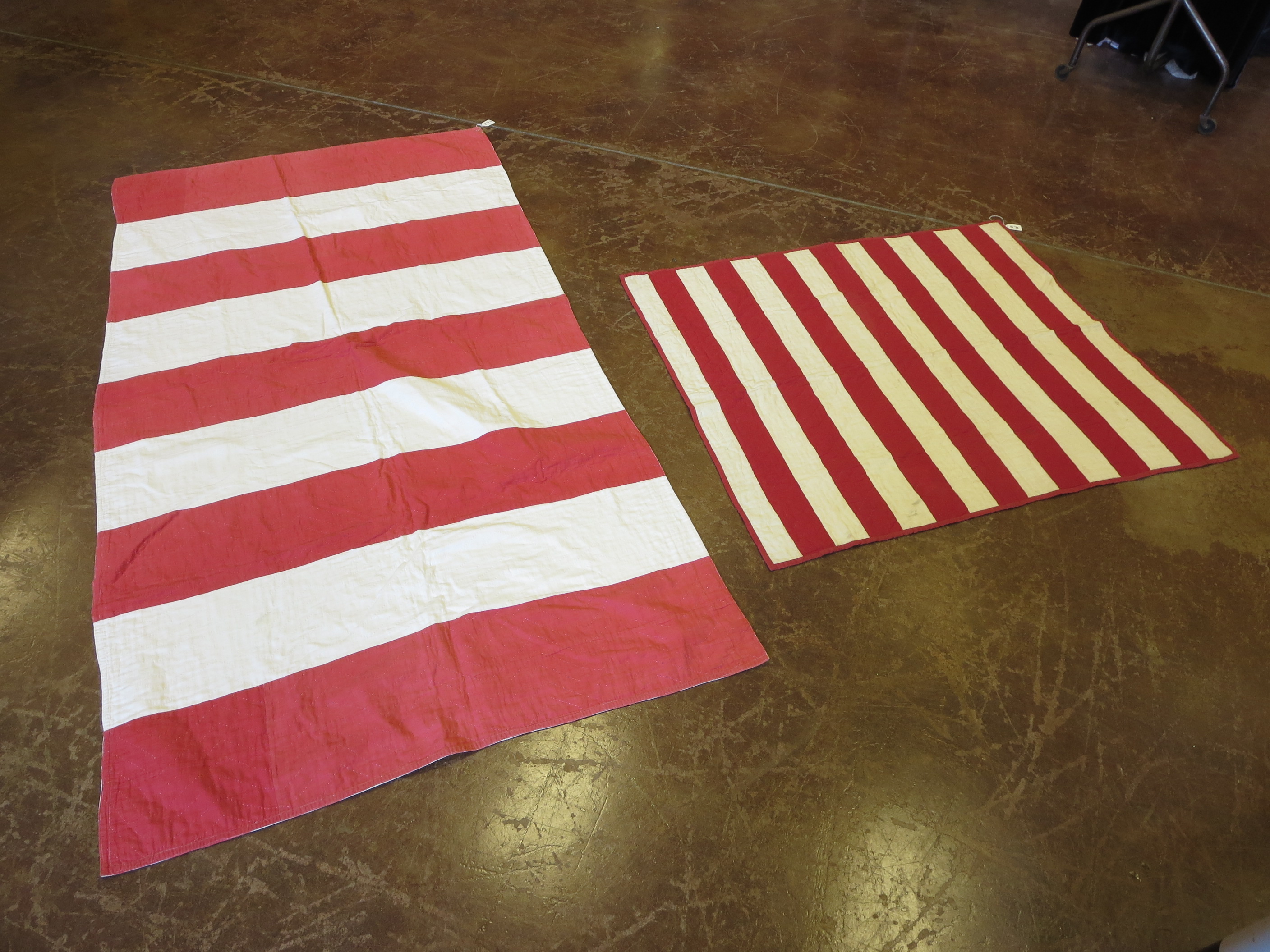 A red and white striped American type quilt and another smaller in cream and red