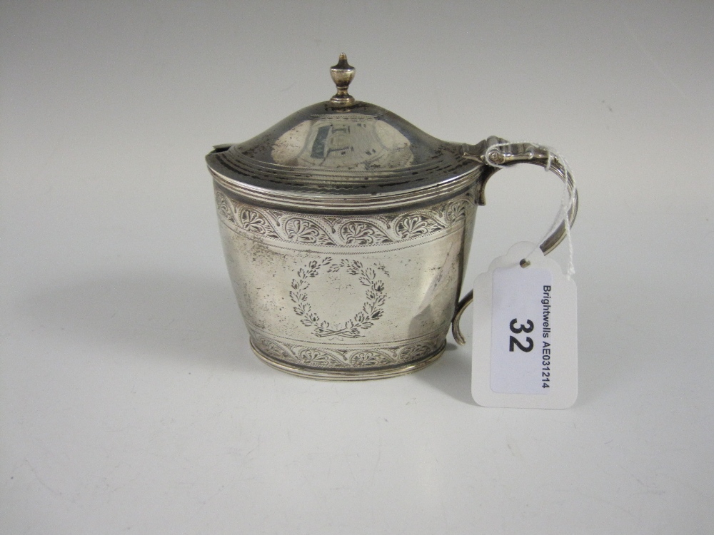 A George III silver oval Mustard Pot with leafage scroll engraved frieze, reeded rims, urn finial,