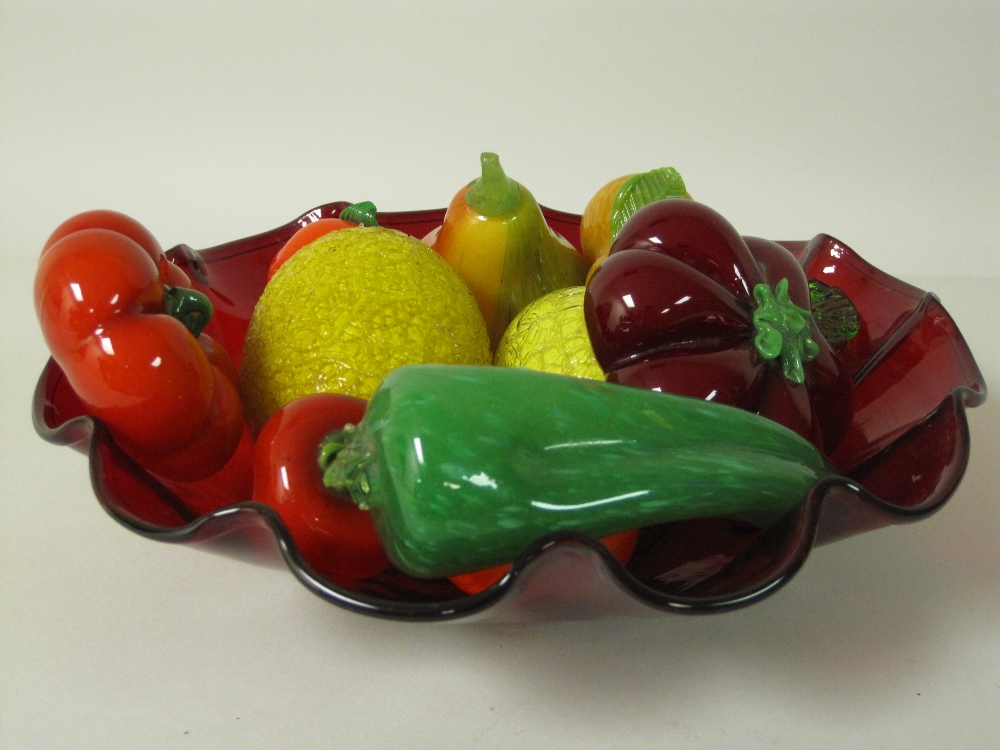 A red glass Bowl with fluted edge, containing a varied collection of glass Fruit, some crackled, all