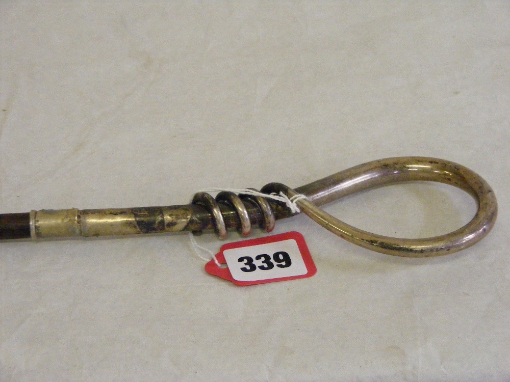 A slim wooden walking stick with an unsual curled metal handle possibly silver.
