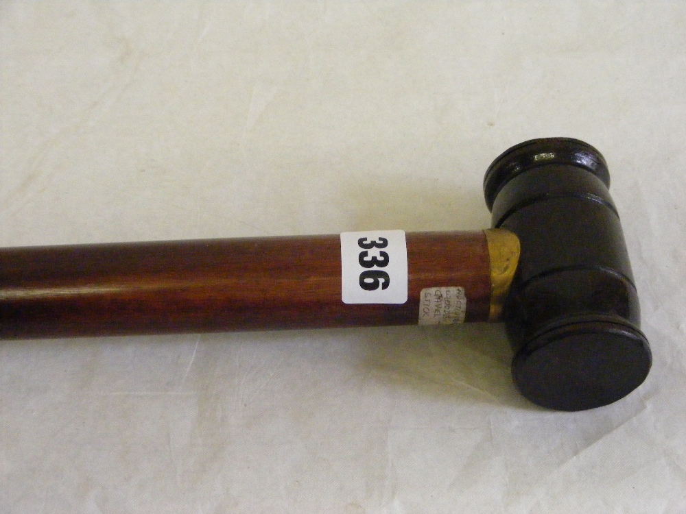A heavy wood walking stick, the handle in the form of an auctioneer's gavel.