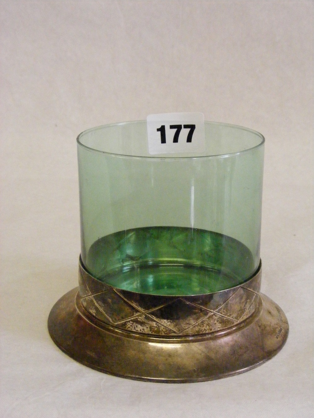 An antique green glass container of circular form raised on a silver base.