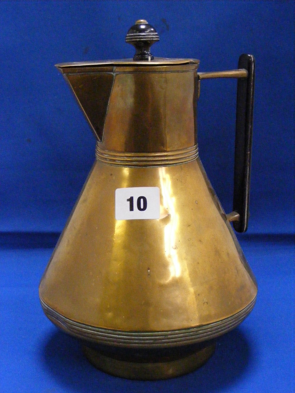 A Christopher Dresser style design brass water jug with ebony handle.