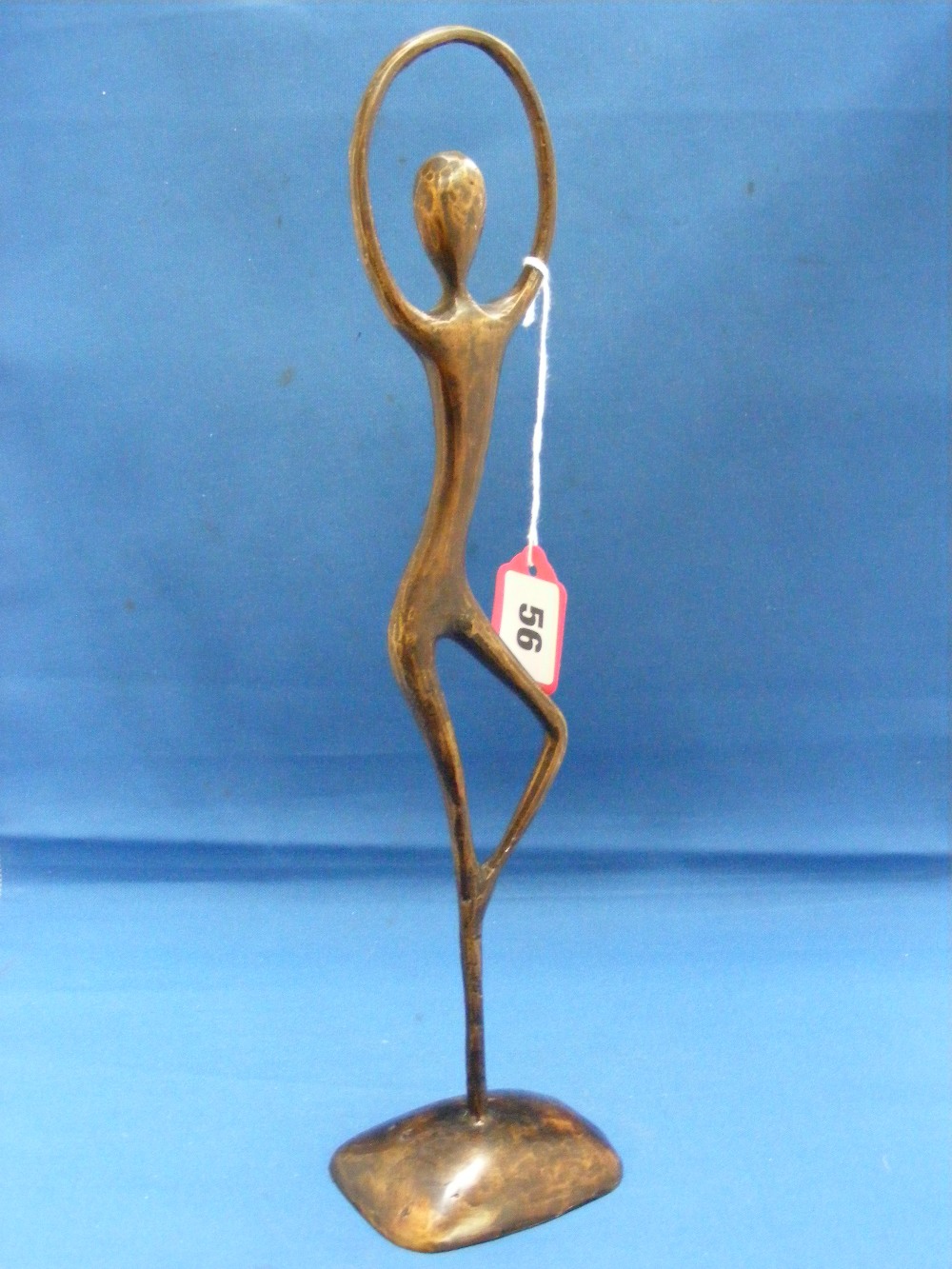 An abstract bronze figure of a ballet dancer of flattened form, her arms reaching above to form a