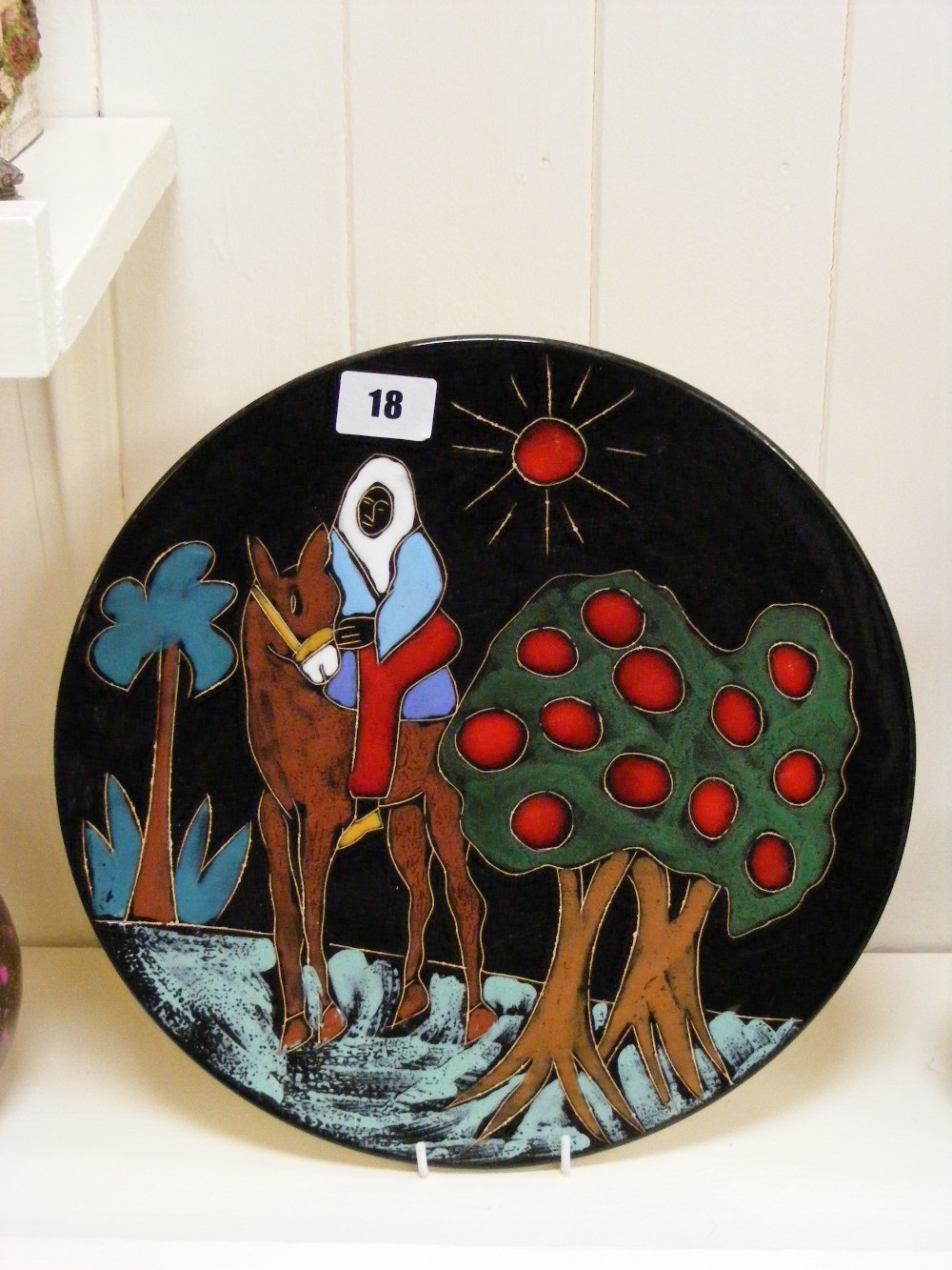 A large wall plate, probably Italian, colourfully decorated with Bedouin Tribesman riding a camel