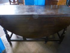 An oval oak drop leaf table on turned legs fitted with a single drawer, est 143 x 136 x 72 cms.