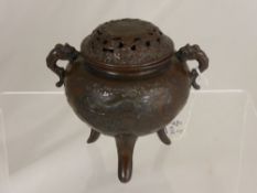 A circa 1900 metal Chinese censer depicting chasing dragons on three feet, est. height 14 cms.