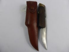 A vintage folding knife having a wooden chequered handle with brass end and uninscribed cartouche,