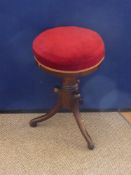 An Antique Mahogany Piano Stool with red velvet upholstery on tripod base.