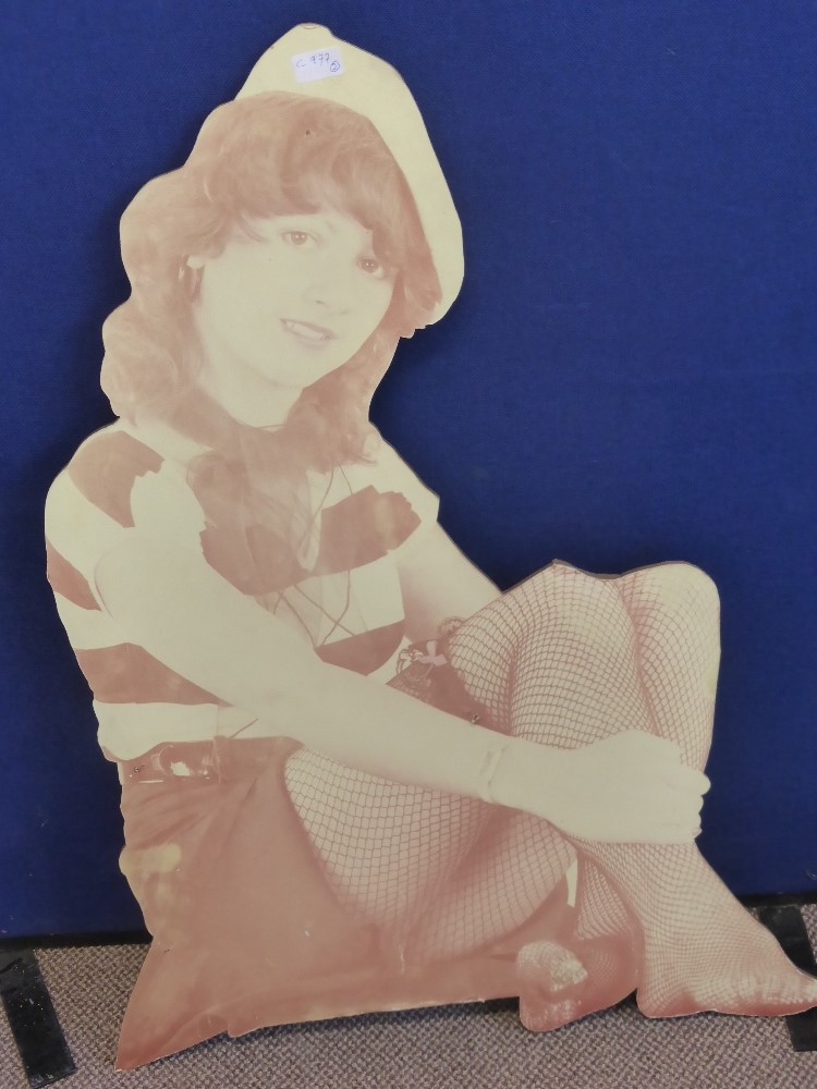 An advertising board depicting a young woman seated from the 1960`s era, 41 cms high.