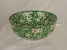 An oriental porcelain bowl depicting cherry blossom on green ground, est. 19 cms. diameter.