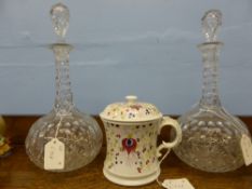 A pair of cut glass decanters (one waf) together with a large ceramic mug with lid, decorated with