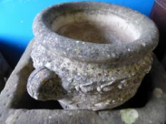 A stone style circular garden planter being two handled with decoration to the pot and the handles,