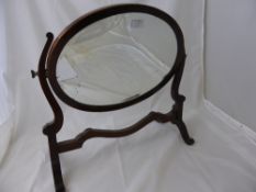 A Victorian mahogany toilet mirror being oval in shape with bevelled glass.