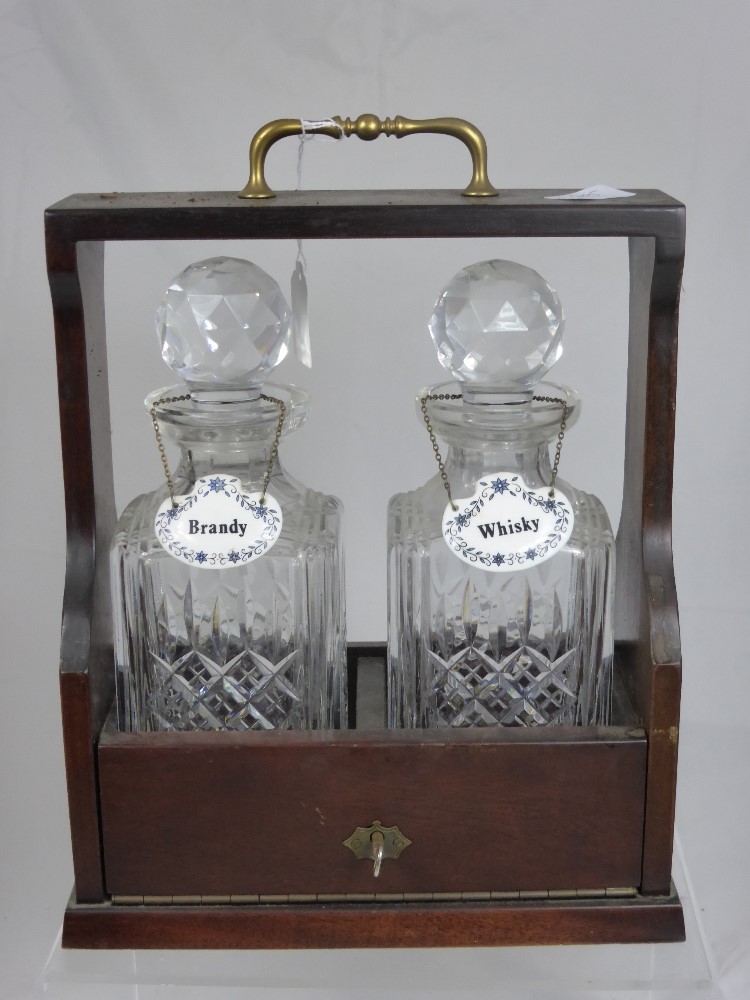 A Mahogany Tantalus with two cut glass decanters and two porcelain labels `Whisky` and `Brandy`