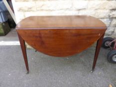 A Victorian oval mahogany drop leaf table being oval in shape on tapered legs and brass castors,