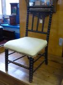 An Edwardian ebonised bedroom chair having bobbin work decoration, the seat covered in a cream