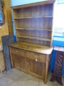 An antique waxed pine dresser with three open shelves to the top, the base having two drawers and