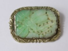 A Chinese Silver Mounted Jade Carved Brooch, the apple green jade amulet carved in the form of a