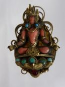 An antique Indian coral and turquoise brooch depicting a crowned figure of Buddha.