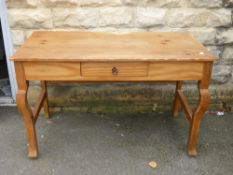 A vintage pine writing table fitted with a single drawer and having shaped front legs with