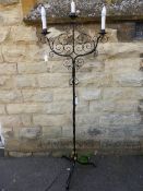 Black wrought iron standard lamp having three branches, decorative scroll work to the top, the