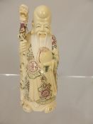 Carved oriental bone figure depicting a wise man holding a small animal, character mark to base,