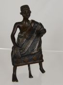 Bronze African Tribal Figure, seated on a stool, dressed in a ceremonial robe.