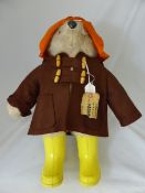 Vintage Paddington Bear, sporting a brown duffel coat, orange hat and yellow wellies.