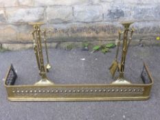 An antique brass fender and two sets of irons.