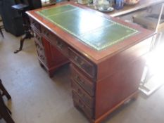 A reproduction desk with eight short drawers and one central drawer with brass handles, green