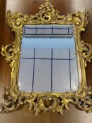 An antique wood and gilded plaster bevelled glass mirror, the mirror having ornate scrolling to