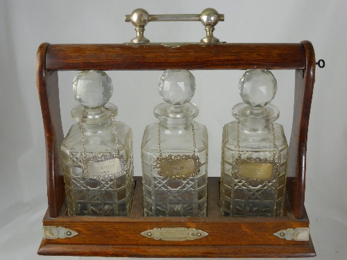 An Oak Cased Tantalus, the set having three cut glass decanters together with three London hallmark