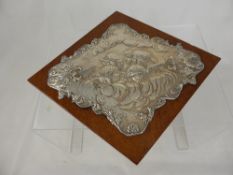 A Silver Plaque, depicting a group of angelic cherubs, supported on a oak base, unmarked.