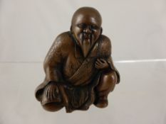 A Japanese bronze covered figure of a sage, the bearded wise man crouching on one knee, wearing a