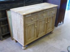 A scrubbed pine cabinet, with three cupboards and three drawers above with a central drawer slide.