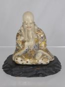 An Antique Japanese Porcelain figure of a wise man, the figure seated in contemplative pose with