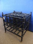 A Victorian Ebonized Canterbury, turned spindles and legs with brass castors, 35 x 48 x 48 cms