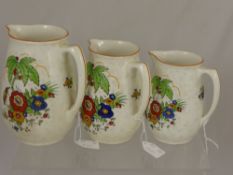 A set of three graduated Crown Ducal jugs decorated with birds together with four Clarice Cliff