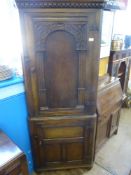 An Antique Oak Corner Cabinet, with double cupboard with decorative carving to door panels and