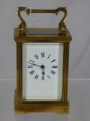 A brass French style carriage clock having a white enamel face with black Roman numerals (with