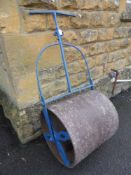 A vintage metal garden roller having a blue painted handle.