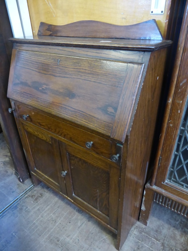 An Edwardian oak bureau, pigeon holes to the interior, drawer below with cupboard under, est. 76 x