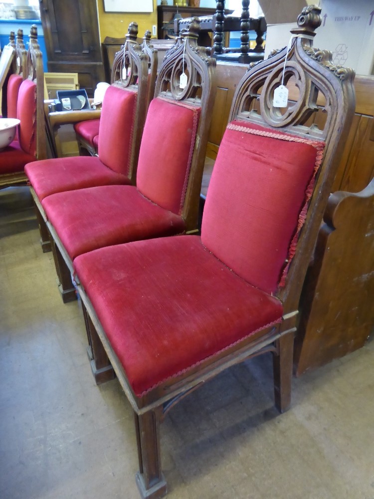 Eight Oak Ecclesiastical Style Dining Chairs, with red velvet upholstery.