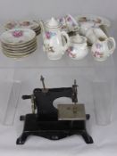 A Porcelain Doll`s Tea Set depicting Flowers, together with a miniature girl`s sewing machine.